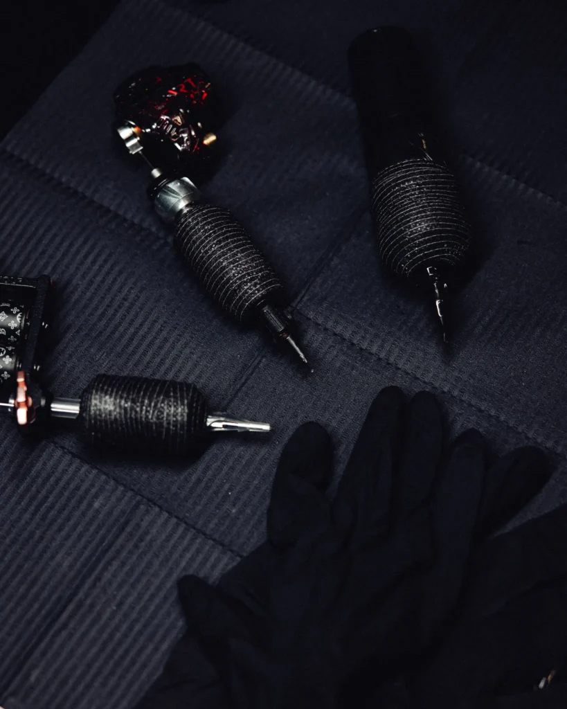Der ultimative Guide für deine permanente Kunst: Welcher Tattoo Stil passt zu dir? 1 Tattoo machines on a dark surface