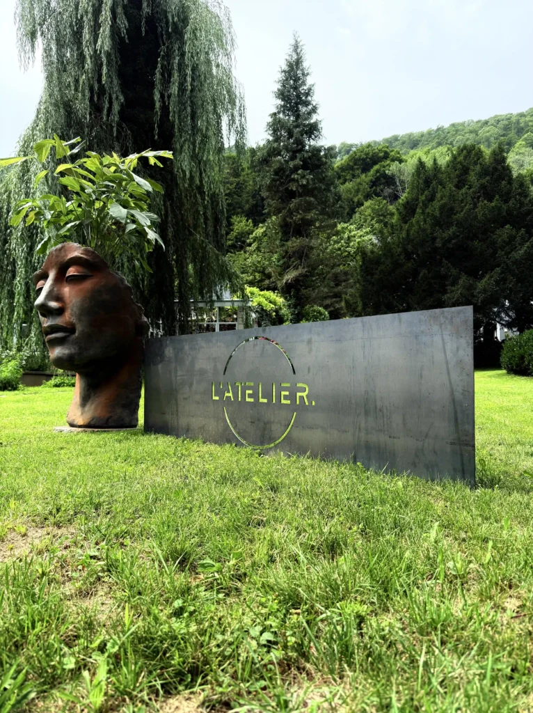 Metal sign of latelier tattoo studio in a green landscape.